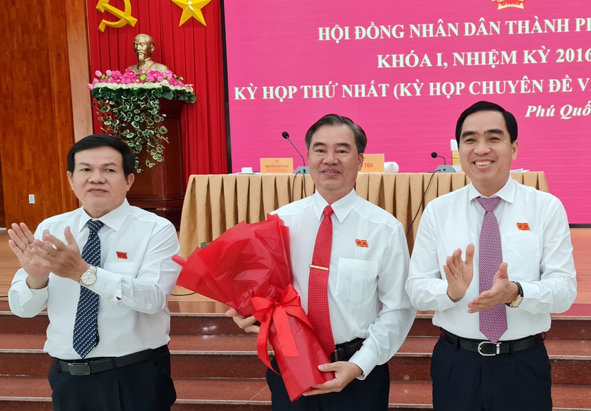Chủ tịch HĐND TP Phú Quốc Nguyễn Đức Kỉnh (trái) và Chủ tịch UBND TP Phú Quốc Huỳnh Quang Hưng (phải) tặng hoa chúc mừng ông Đoàn Văn Tiến